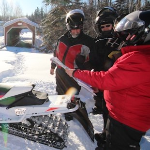 Snowmobilers and a covered bridge in Kamouraska